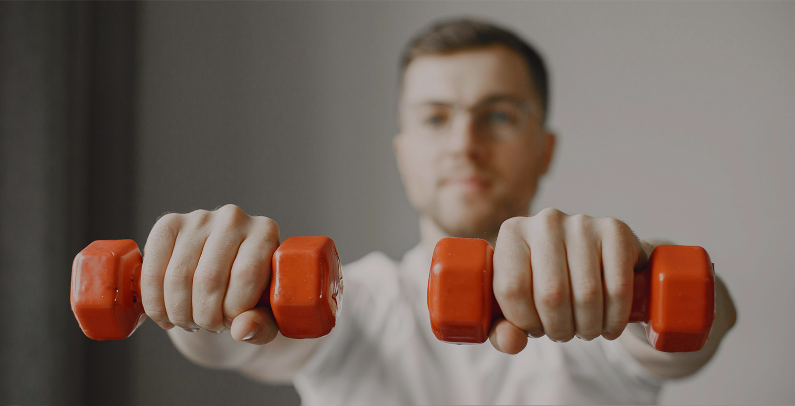 A person holding orange dumbbells during a wellness workout session